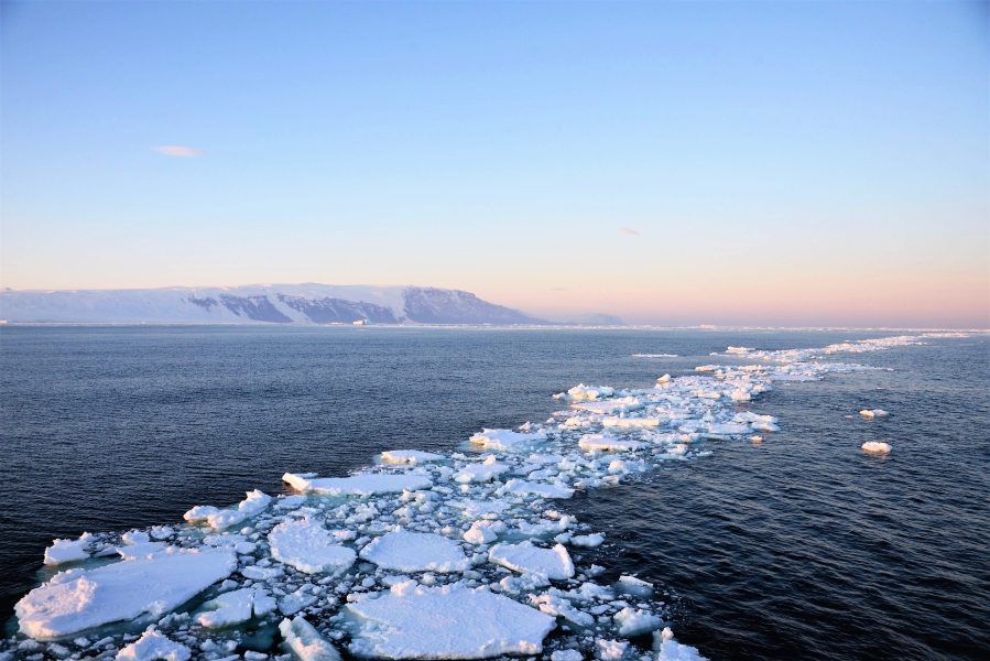 Breaking sea ice like seen on icy waters of Antarctica. Glaciers seen in the background